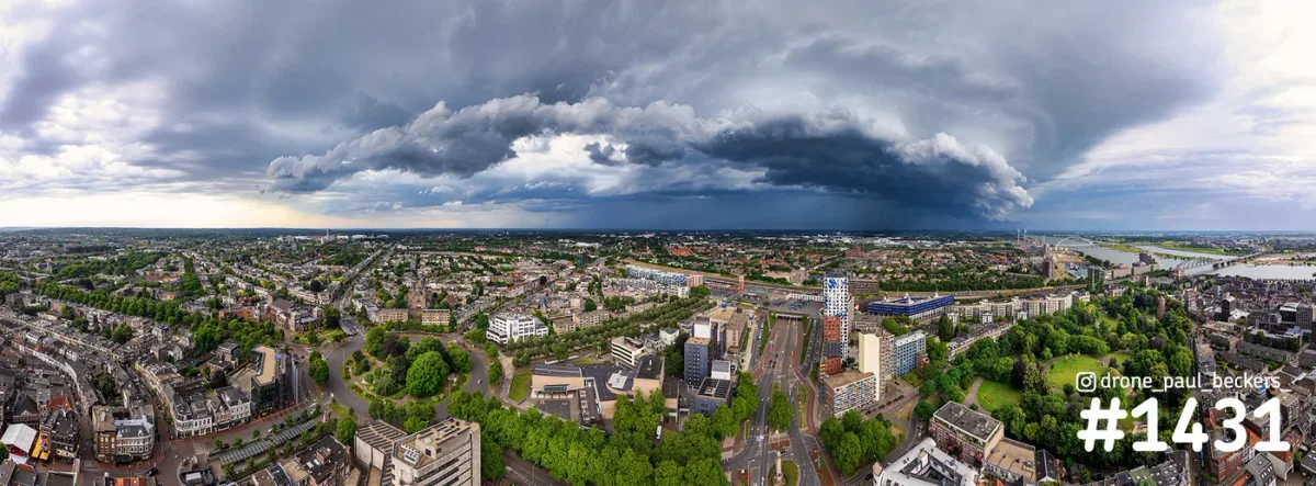 Panoramische luchtfoto van Nijmegen met donkere onweerswolken boven het centrum, Kronenburgerpark en de Waal
