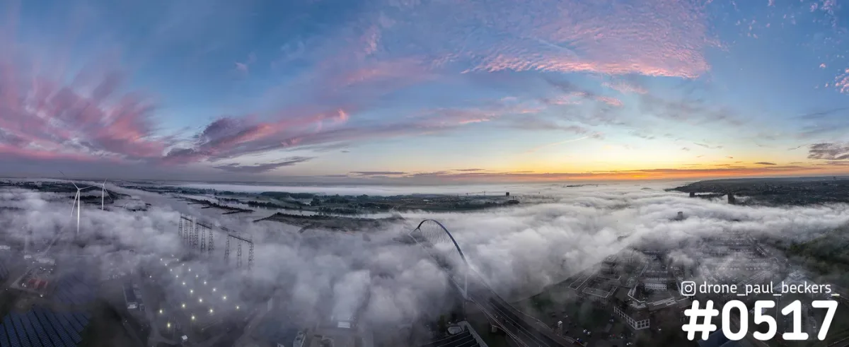 Panorama van De Oversteek in Nijmegen boven een dik mistdek, met roze wolken en een oranje gloed aan de horizon