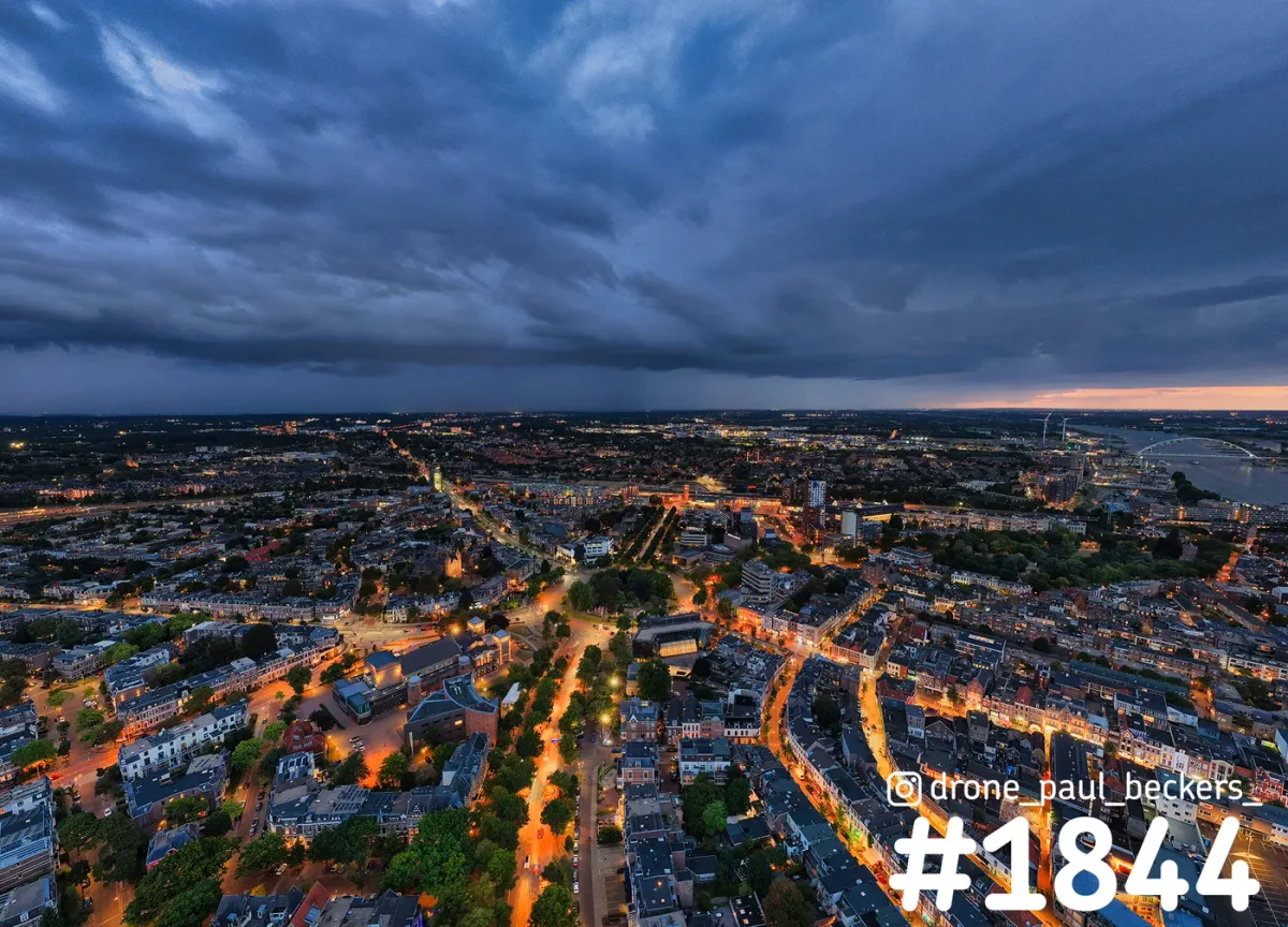 Luchtfoto van Nijmegen bij Keizer Karel Plein in de avondschemering, oranje straatlicht onder donkere wolken