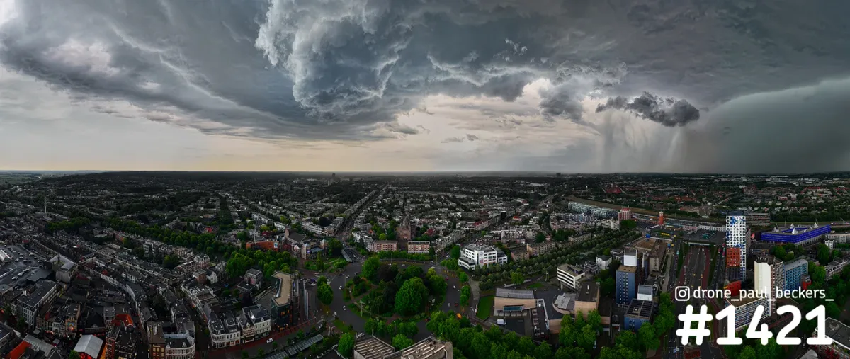Luchtfoto van Nijmegen met donkere buienwolken en een regenvlaag boven Keizer Karel Plein en het Stationsgebied