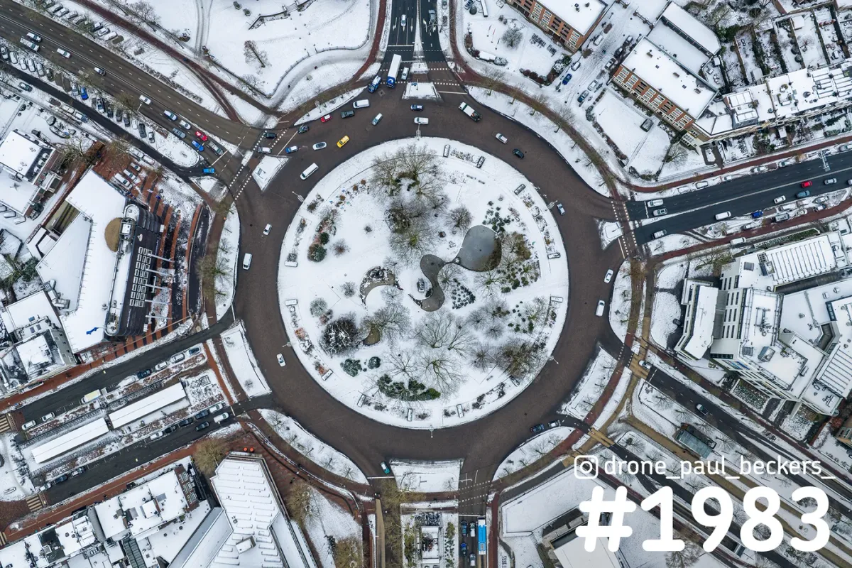 Luchtfoto van het Keizer Karel Plein in Nijmegen onder een laag sneeuw, met de ronde rotonde en het park in het midden