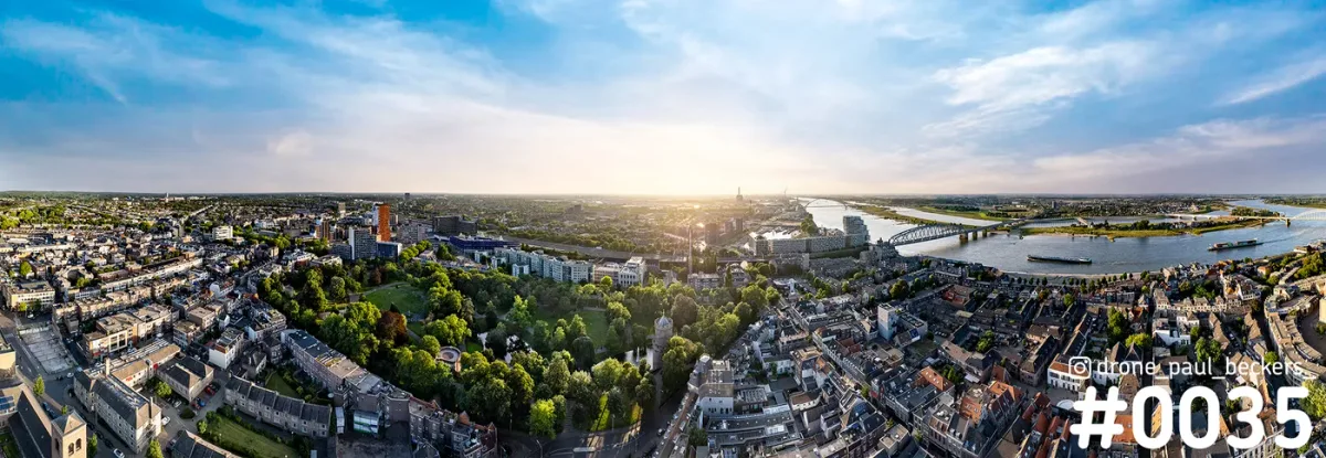 Panoramische luchtfoto van Nijmegen met het Kronenburgerpark, de Waal en een brug in het licht van de laagstaande zon