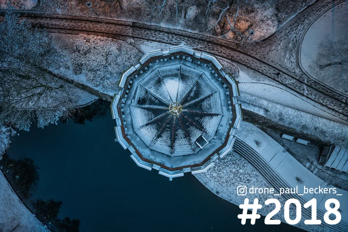 Luchtfoto van boven op een besneeuwd paviljoen naast de vijver in het Kronenburgerpark in Nijmegen, in blauw schemerlicht