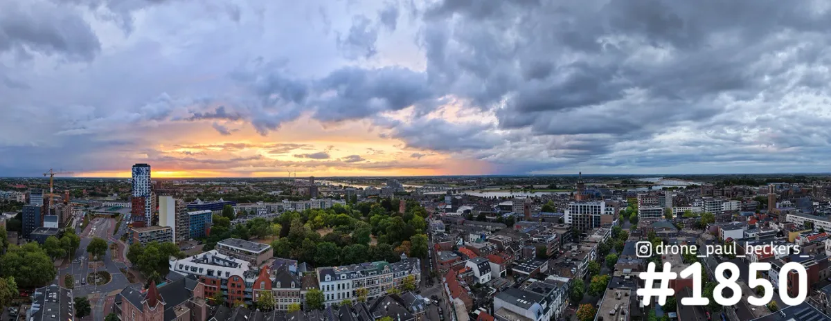 Panorama van het centrum van Nijmegen met Kronenburgerpark en een oranje gloed onder zwaar wolkendek