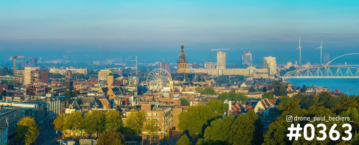 Luchtfoto panorama van Nijmegen met de Stevenskerk, een reuzenrad van de kermis en de Waal met brug in het ochtendlicht