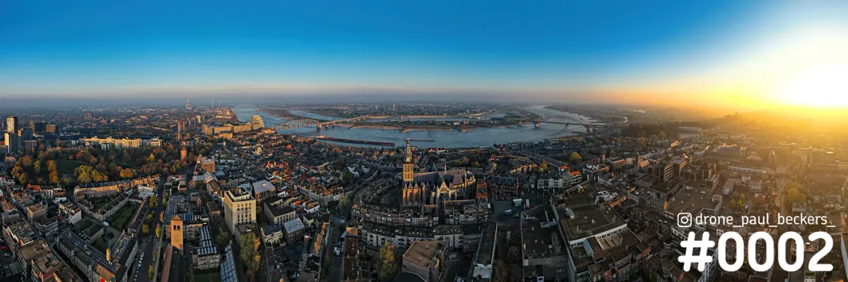 Panoramische luchtfoto van Nijmegen met de Stevenskerk, de Waal en de Waalbrug bij laagstaande zon en herfstkleuren