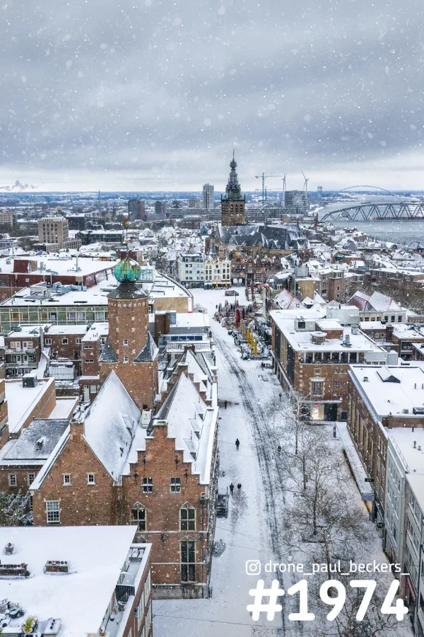 Luchtfoto van het besneeuwde centrum van Nijmegen met Stevenskerk en De Oversteek aan de Waal tijdens sneeuwval