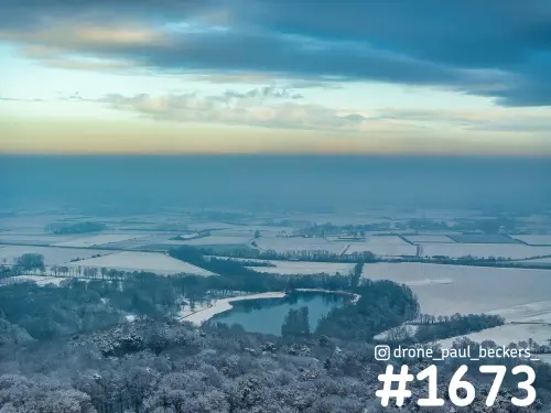 Luchtfoto van de Duivelsberg bij Nijmegen in de sneeuw, met een bevroren plas en besneeuwde akkers van de Ooijpolder