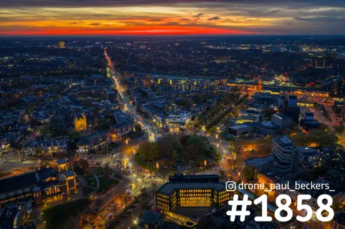 Luchtfoto van Nijmegen in de avondschemering met een rood-oranje horizon boven Keizer Karelplein en het stationsgebied