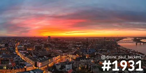 Luchtfoto van Nijmegen-centrum in de schemering met Stevenskerk, de Waal en een rood-oranje lucht