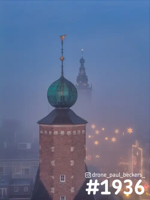 Luchtfoto van een bakstenen toren met groene koepel in de mist, centrum Nijmegen, met lichtsterren boven de straat