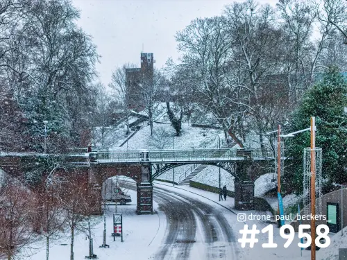 Stenen boogbrug over een besneeuwde weg in het Valkhof gebied in Nijmegen, met sneeuwval en kale bomen