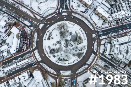 Luchtfoto van het Keizer Karel Plein in Nijmegen onder een laag sneeuw, met de ronde rotonde en het park in het midden