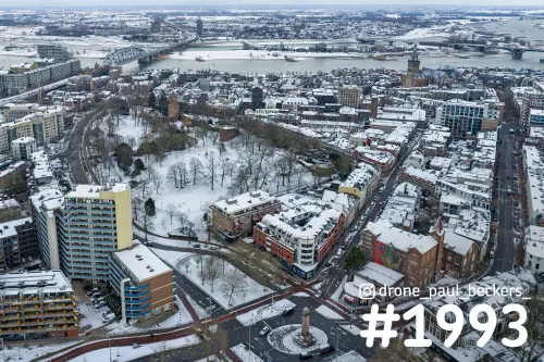 Luchtfoto van het besneeuwde Kronenburgerpark in Nijmegen met de Stevenskerk en de Waal op de achtergrond
