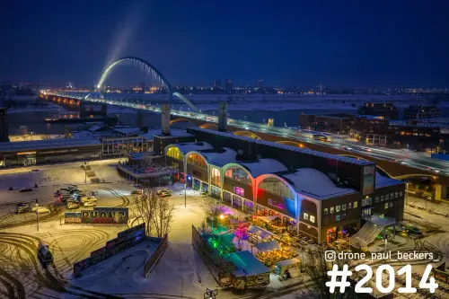 Luchtfoto van De Oversteek in Nijmegen in het avondlicht, met een besneeuwde hal met gekleurde verlichting in Lent