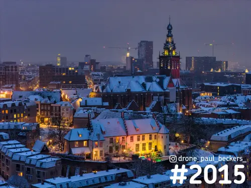 Luchtfoto van de Stevenskerk in het centrum van Nijmegen in de avond, met besneeuwde daken en verlichte ramen
