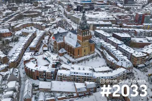 Luchtfoto van de Stevenskerk in het centrum van Nijmegen na sneeuwval, met besneeuwde daken rond de Grote Markt