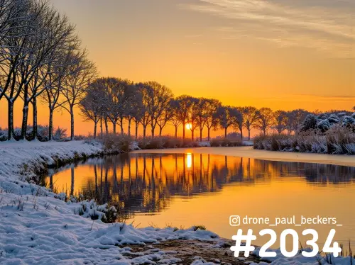 Sneeuw langs een waterloop in de Ooijpolder bij Nijmegen, met laagstaande zon achter kale bomen en oranje weerspiegeling