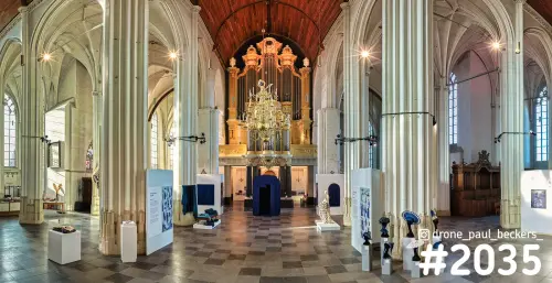 Interieur van de Stevenskerk in Nijmegen met het orgel, kroonluchter en witte tentoonstellingspanelen tussen de zuilen