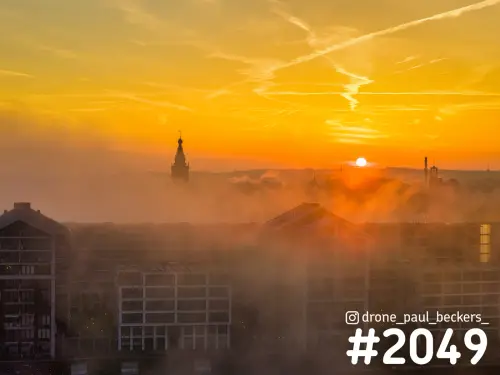 Luchtfoto van de Handelskade in Nijmegen met mist bij zonsopkomst, de toren van de Stevenskerk steekt boven de nevel uit