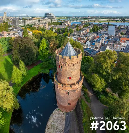 Luchtfoto van de bakstenen toren in het Kronenburgerpark in Nijmegen met fontein in de vijver en de Waal in de verte