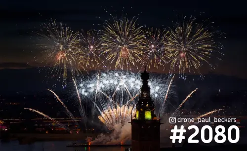 Luchtfoto van vuurwerk boven de Waal bij de Stevenskerk in Nijmegen, met gouden en witte uitbarstingen in de nacht