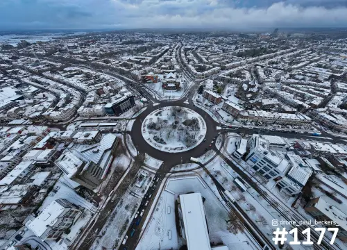 Luchtfoto van een besneeuwde rotonde met rond plantsoen in het centrum van Nijmegen, omgeven door witte daken