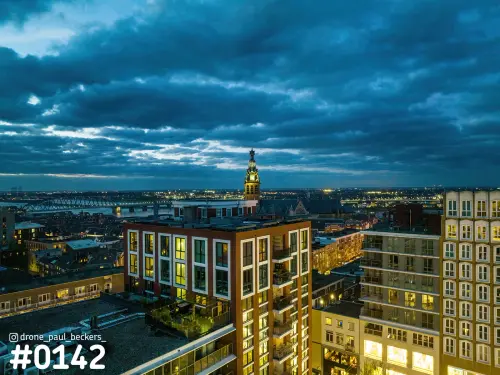 Luchtfoto van het centrum van Nijmegen in de avondschemering, met de toren van de Stevenskerk en de Waal in de verte