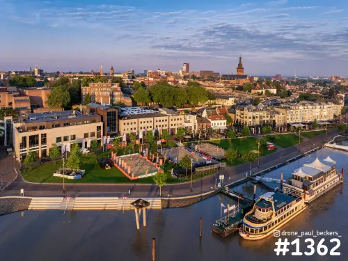 Luchtfoto van het centrum van Nijmegen met rondvaartboten aan de kade en de Stevenskerk in gouden licht