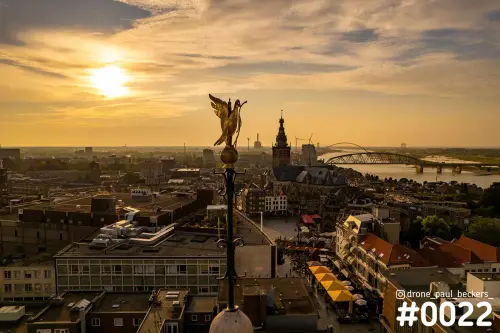 Luchtfoto van het centrum van Nijmegen met Stevenskerk en de Waal in gouden licht, en een gouden beeld op de voorgrond