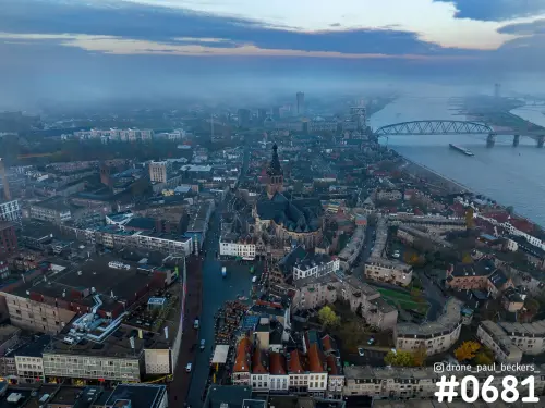 Luchtfoto van het centrum van Nijmegen met de Stevenskerk, de Waalkade en de Waal onder een laag mist bij schemerlicht