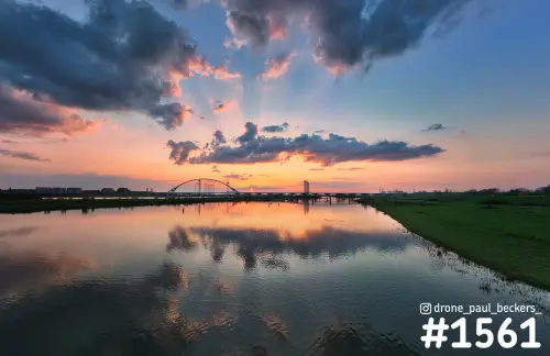 De Oversteek in Nijmegen-Lent bij zonsondergang, met wolken en oranje lucht weerspiegeld in de Nevengeul