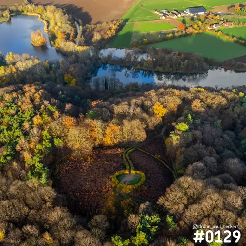 Luchtfoto van herfstbos op de Duivelsberg met een ronde kuil en kronkelende groene haag, met plassen en weilanden erachter
