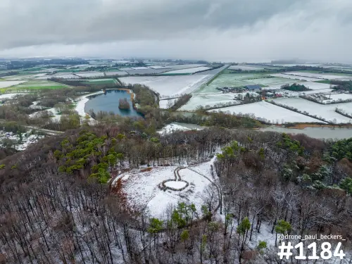 Luchtfoto van de Duivelsberg bij Nijmegen onder een zware lucht, met sneeuw op het bos, een open heuveltop en besneeuwde akkers