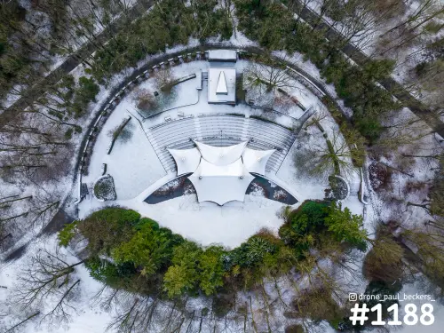 Luchtfoto van een openluchttheater bij de Goffert in Nijmegen, met sneeuw op de zitrijen en het witte tentdak