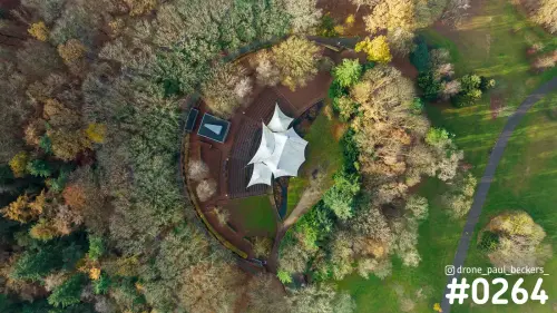 Luchtfoto recht van boven van een halfronde tribune met wit tentdak in de Goffert in Nijmegen, omringd door herfstbomen