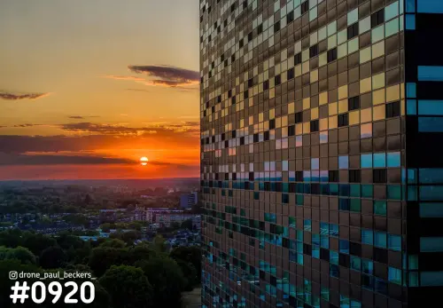 Luchtfoto van een hoge toren bij de Goffert in Nijmegen met zonsondergang die oranje weerkaatst in de glazen gevel