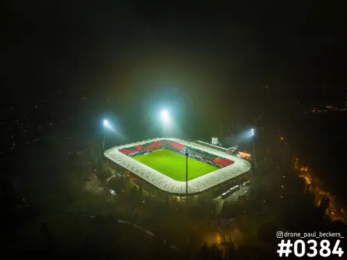 Luchtfoto van het Goffertstadion in Nijmegen bij avondlicht, met felle lichtmasten en mist rond het groene veld