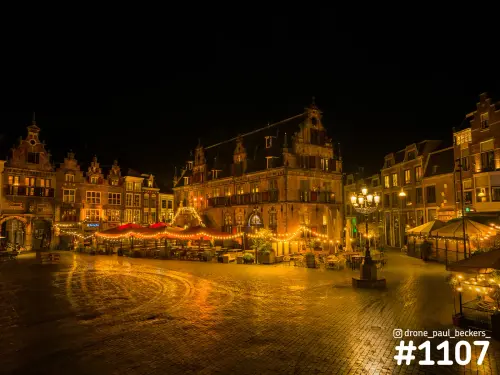 Avondbeeld van de Grote Markt in Nijmegen met natte keien, verlichte terrassen en lichtslingers bij de trapgevels