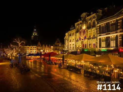 Grote Markt Nijmegen in de avond met verlichte terrasparasols, natte keien en de toren van de Stevenskerk achter de gevels