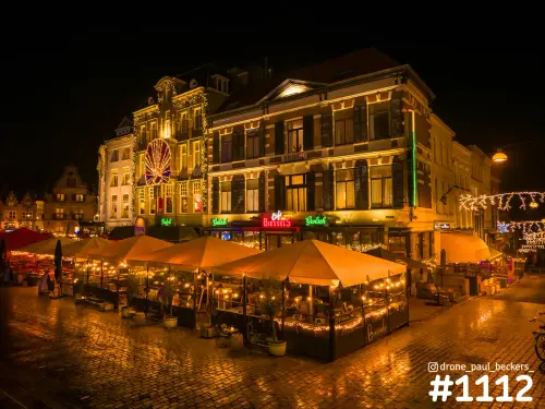 Grote Markt in Nijmegen bij avond met verlichte gevels, terrassen onder oranje parasols en glanzende natte keien