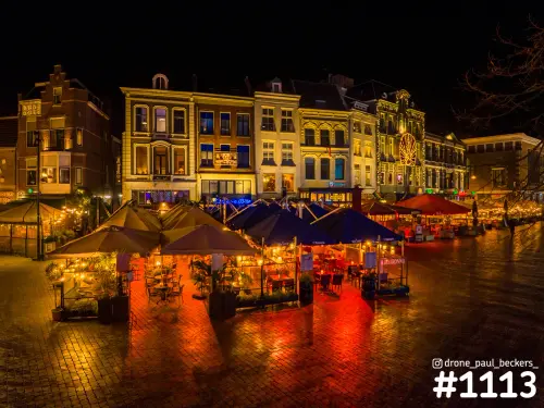 Terrassen met parasols op de Grote Markt in Nijmegen 's avonds, natte straatstenen weerkaatsen oranje licht