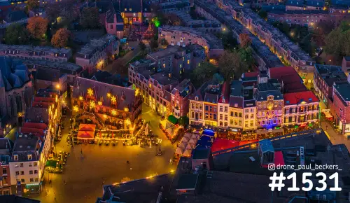Luchtfoto van de Grote Markt in Nijmegen in de avond, met verlichte gevels en sterren op het stadhuis