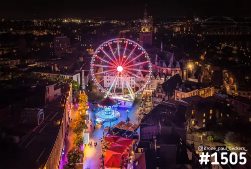Luchtfoto van het reuzenrad en de kermis op de Grote Markt in Nijmegen bij nacht, met de Stevenskerk en De Oversteek