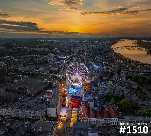 Luchtfoto van de kermis op de Grote Markt in Nijmegen bij zonsondergang, met reuzenrad, Stevenskerk en de Waal