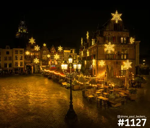 Grote Markt Nijmegen in de avond met lichtsterren op de gevels, natte klinkers en de toren van de Stevenskerk