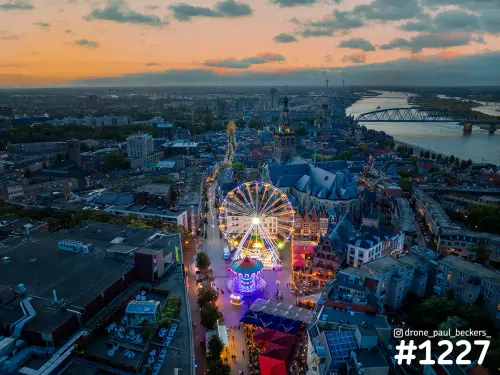 Luchtfoto van het verlichte reuzenrad op de Grote Markt in Nijmegen bij zonsondergang, met de Stevenskerk erachter