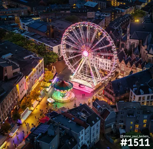 Luchtfoto van het reuzenrad en de draaimolen op de Grote Markt in Nijmegen, 's avonds verlicht naast de Stevenskerk