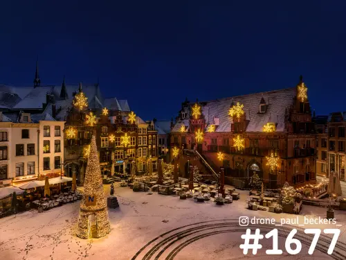 Luchtfoto van de Grote Markt in Nijmegen bij avond met sneeuw, verlichte kerstboom en sneeuwvlokken op de gevels