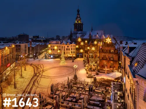 Luchtfoto van de besneeuwde Grote Markt in Nijmegen in de avond, met verlichte kerstboom en de Stevenskerk